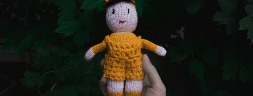 A hand holds a small doll